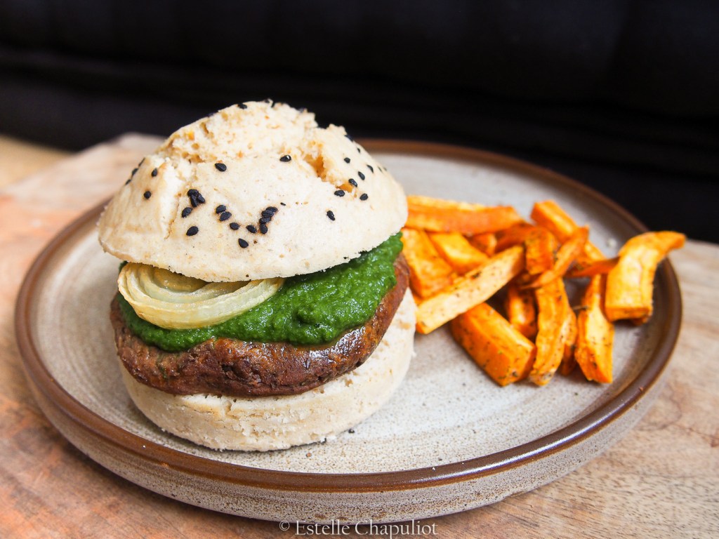 Burger végétal : pain vapeur sans gluten, steak de lentilles beluga, frites de patate douce au four aux herbes, sauce verte, oignons