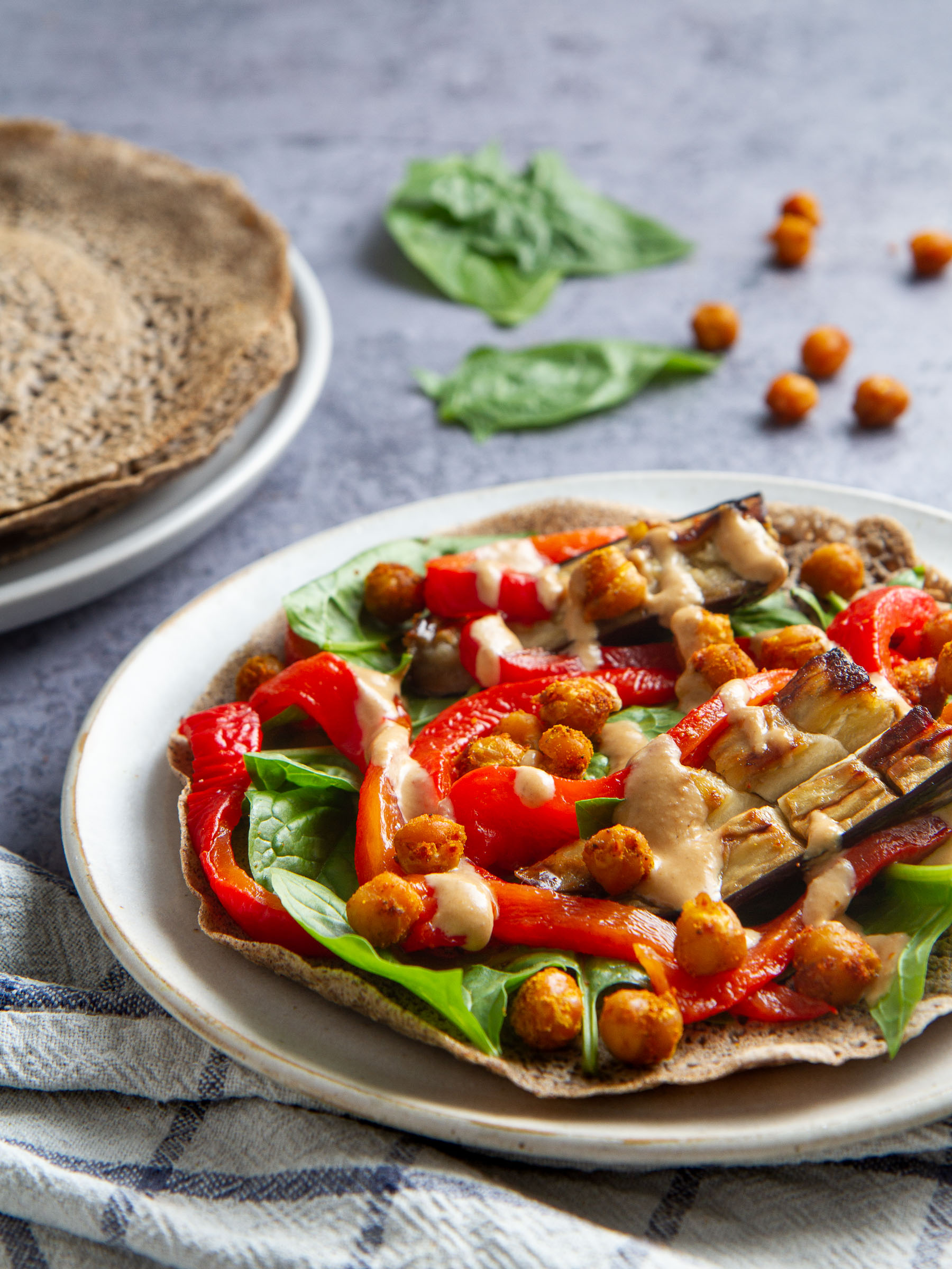 Galettes de sarrasin garnies aux pois chiches et aubergines rôtis, poivronnade, pousses d'épinards et sauce tahin-miso (vegan, sans gluten)